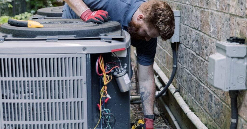 Technician servicing an outdoor AC unit capacitor